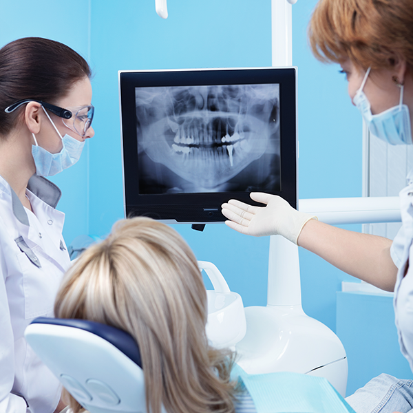 Dental assistant showing patient digital x-ray